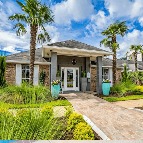 A house with a front yard featuring a palm tree and a brick pathway leading to the entrance.